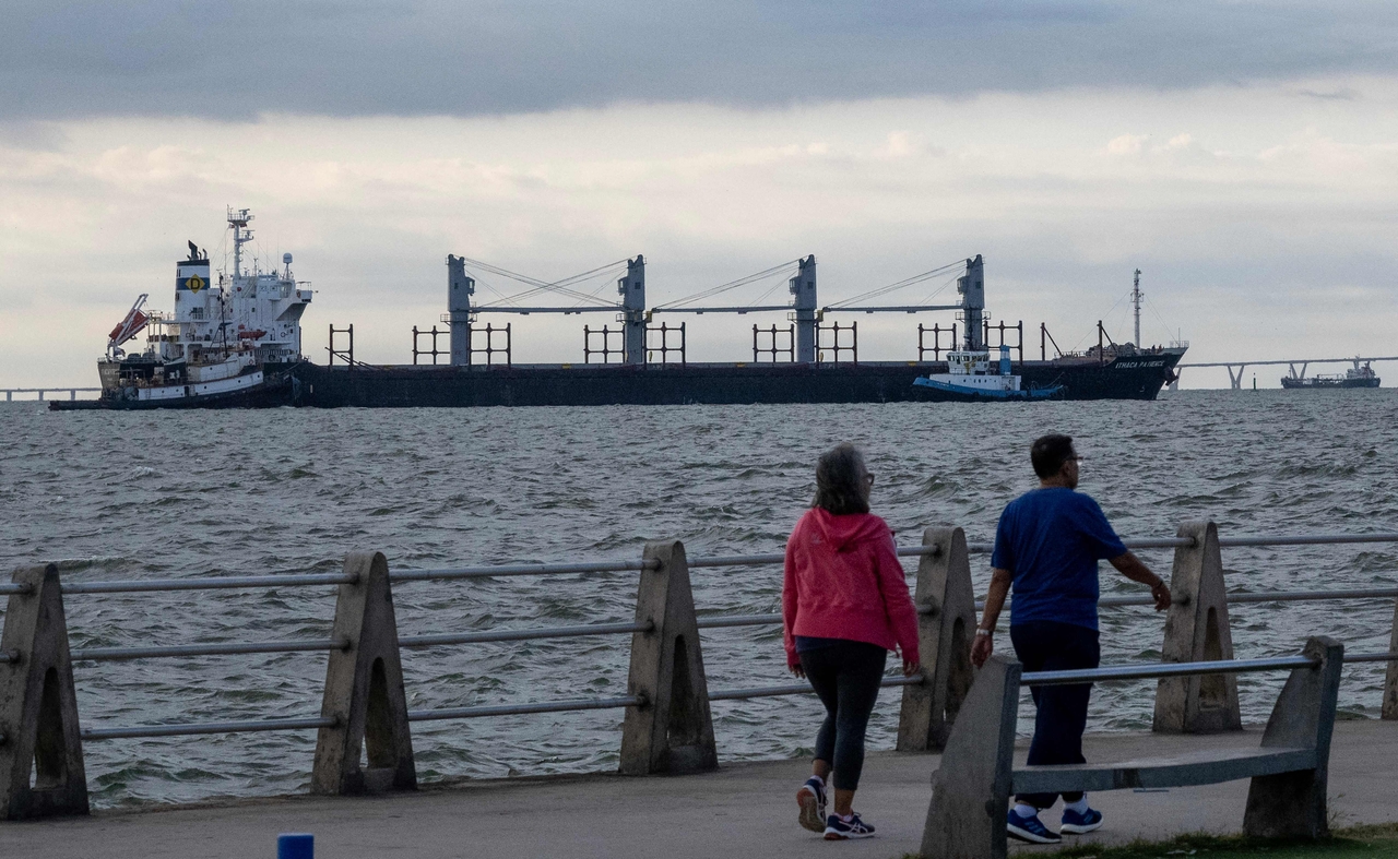 People walk through a walkway as crude oil tankers are seen anchored on Lake Maracaibo in the background on Wednesday.   AFP-Yonhap