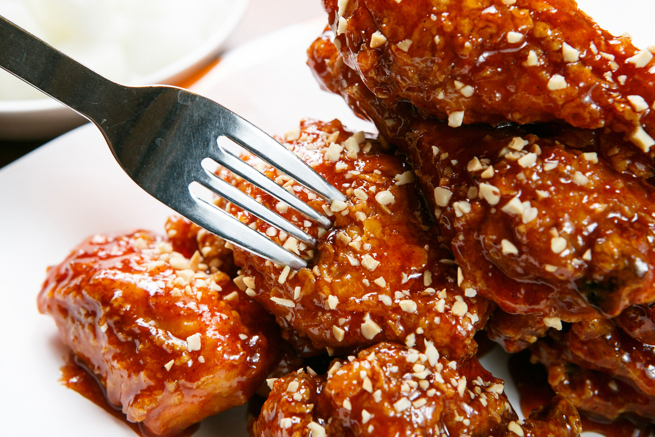 Korean yangnyeom chicken coated in glossy red sweet and spicy gochujang glaze served on a plate