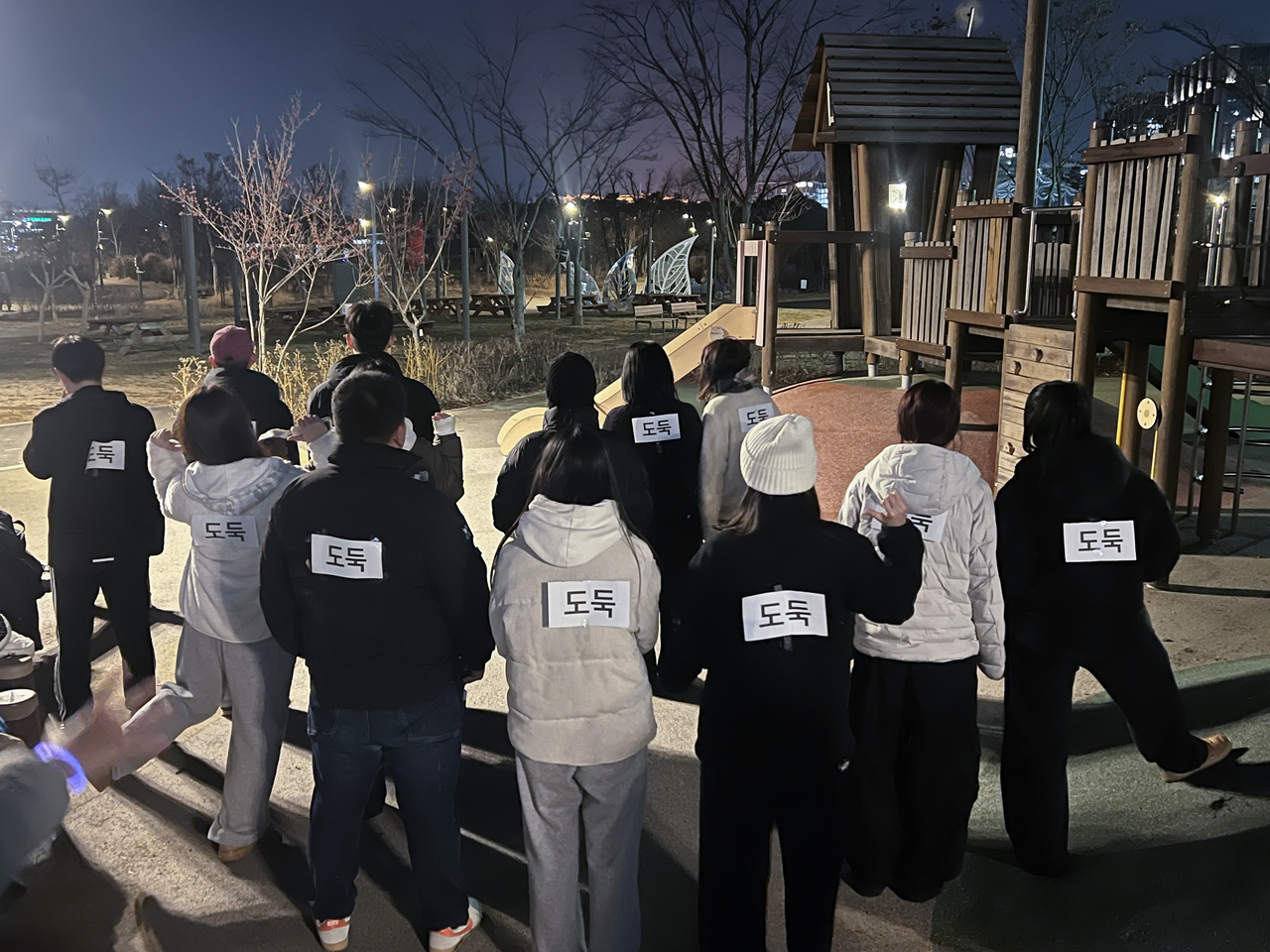 지난해 12월 24일 서울 강서구 서울식물원 잔디밭에서 열린 ‘경찰과 도둑’ 놀이 모습. 도둑 역할을 맡은 사람들이 등에 ‘도둑’ 종이가 붙여져 있다. [연합]