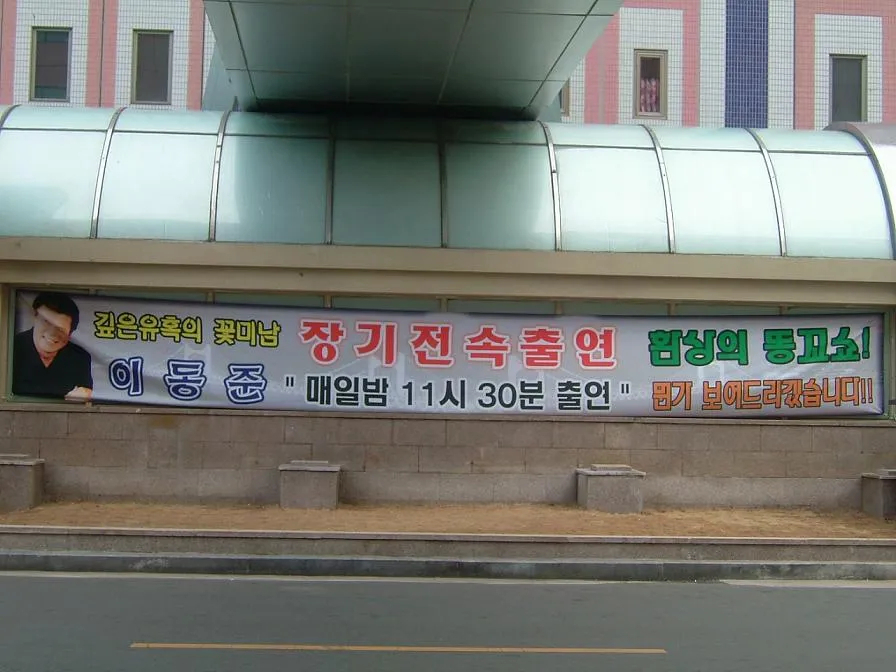 A photograph of a nightclub poster in Busan showing Lee Dong-jun's face next to the phrase "Fantastic Butthole Show," circulated online in the late 2000s. (Source unknown)