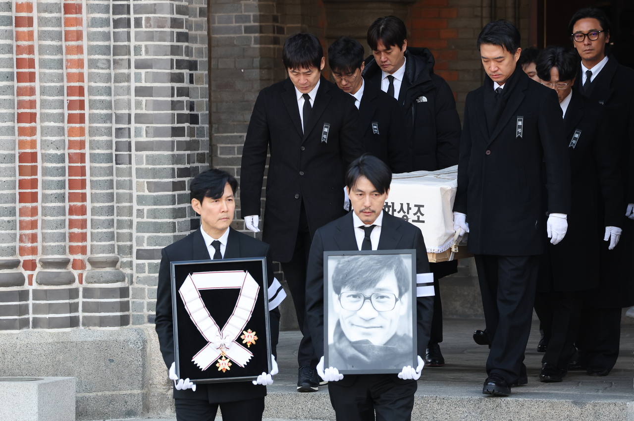 Actors Jung Woo-sung (right) and Lee Jung-jae carry the late actor Ahn Sung-ki’s portrait and the Geumgwan Order of Cultural Merit after a funeral Mass at Myeongdong Cathedral in Seoul on Friday. (Yonhap)