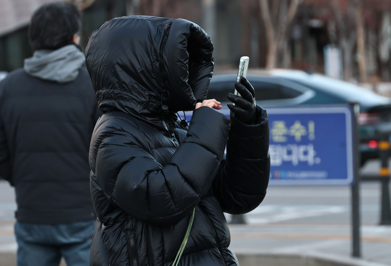 A commuter bundled up with hat and face cover braving severe cold at Gwanghwamun Intersection in central Seoul