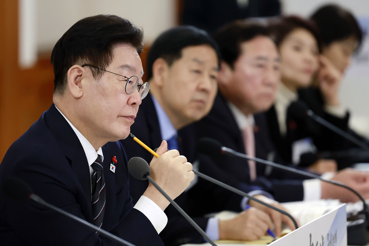 President Lee Jae Myung (left) attends a meeting at the presidential office in Seoul on Friday, to report to the public a set of ambitious policy initiatives for this year aimed at supporting what it calls a "great economic leap" to turn South Korea into a global leader in key industries. (Yonhap)