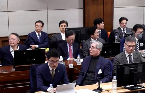 Former President Yoon Suk Yeol (L) attends his insurrection trial, along with other defendants and their respective lawyers, at the Seoul Central District Court in the capital on Friday, in this photo provided by the court. (Yonhap)