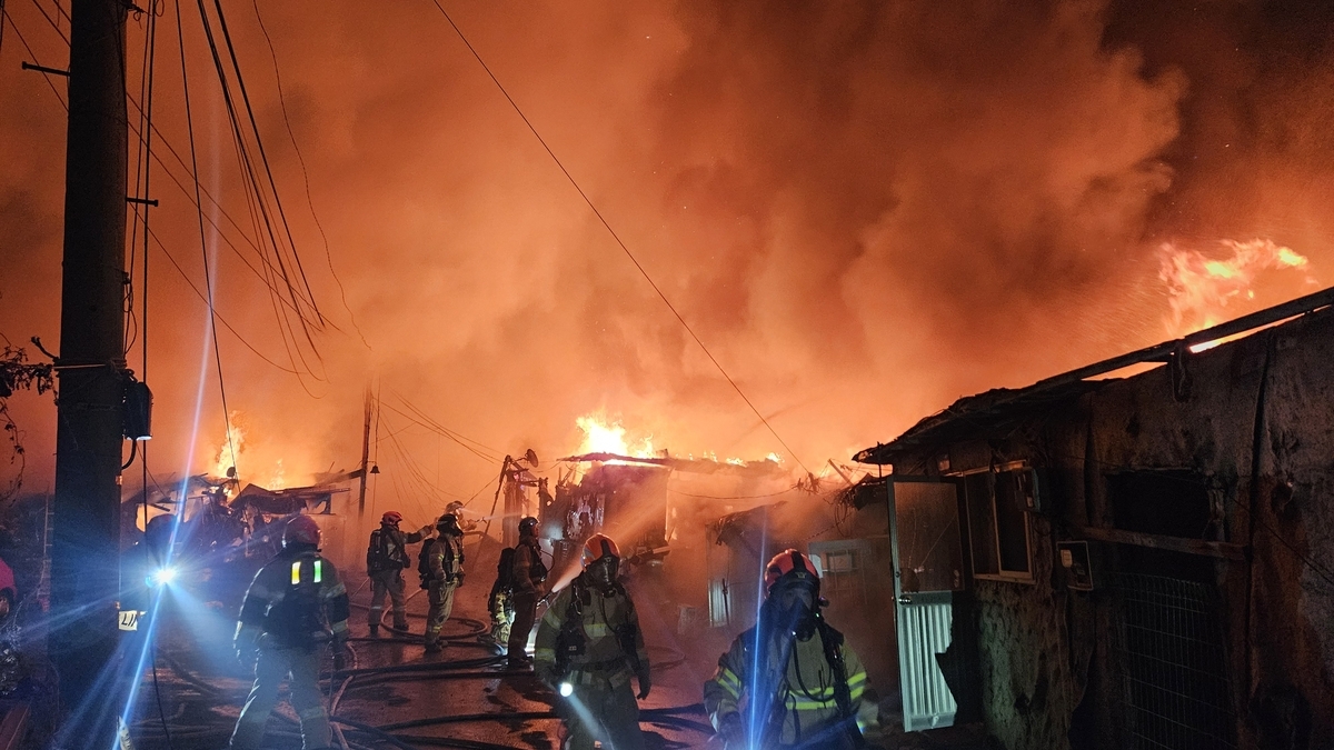 Firefighters are working to contain the fire at Guryong Village, a low-income town in southern Seoul on Friday. (Seoul Fire Services via Yonhap)