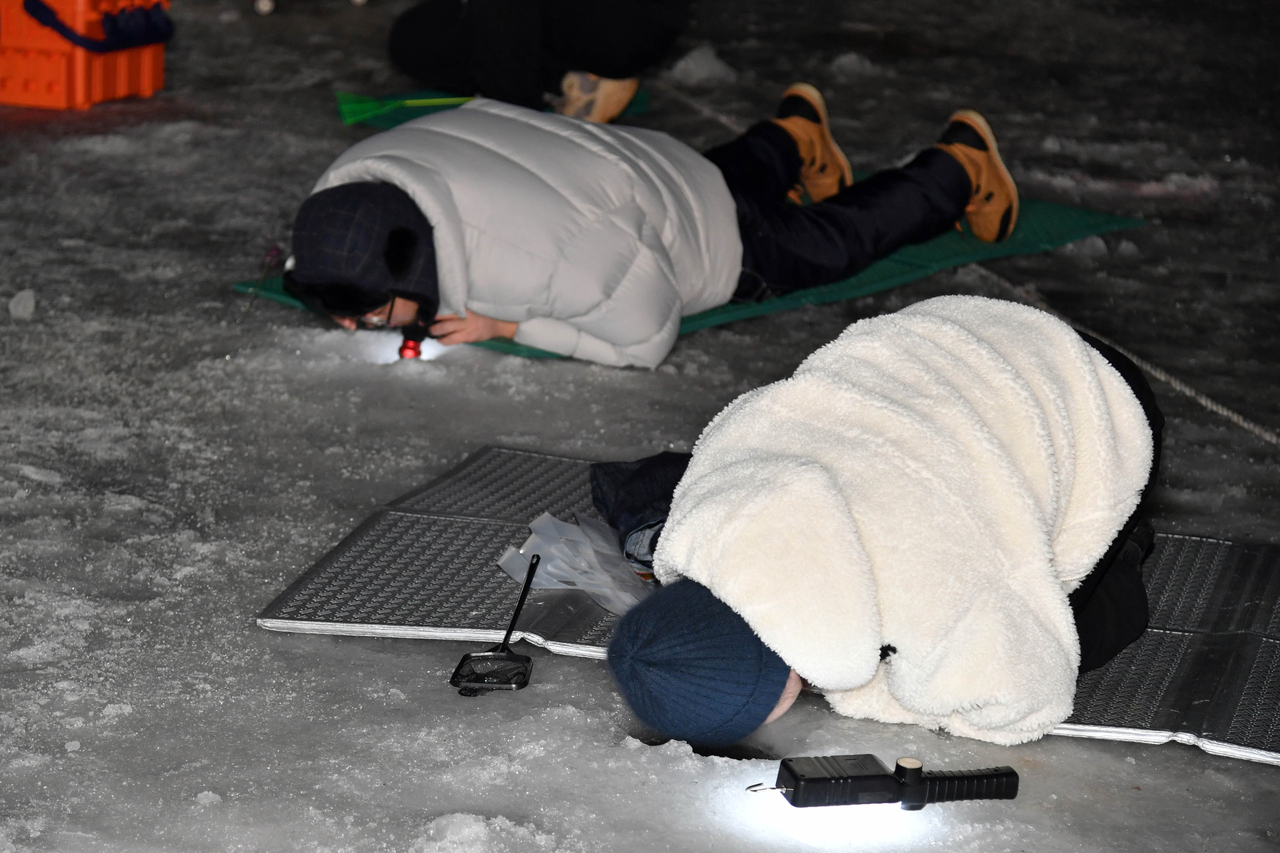Tourists take part in ice fishing in Hwacheon County, Gangwon Province, on Saturday. (Yonhap)