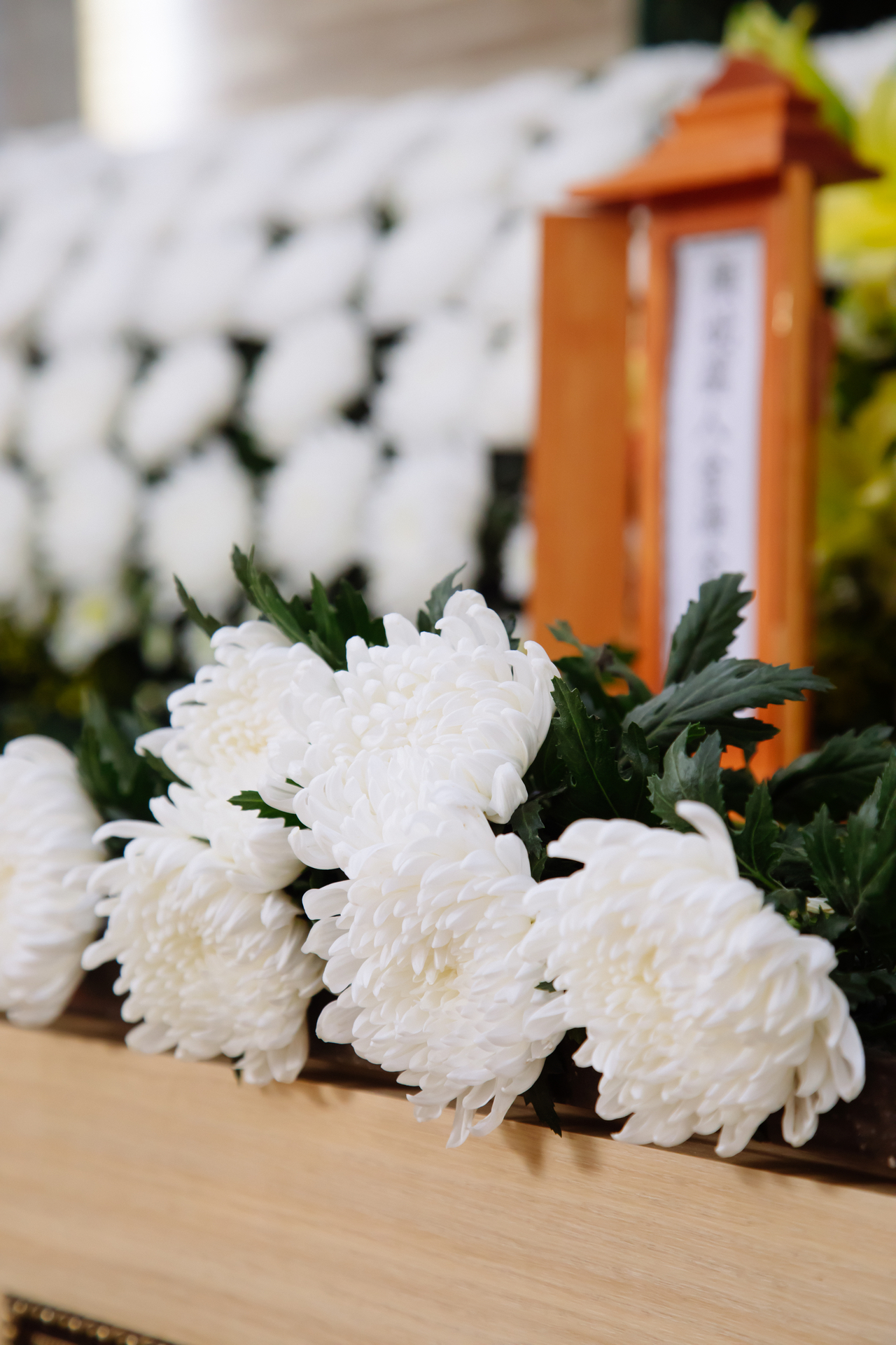 Memorial altar with white chrysanthemums and condolence flower wreaths inside a Korean hospital funeral hall during a three-day mourning period