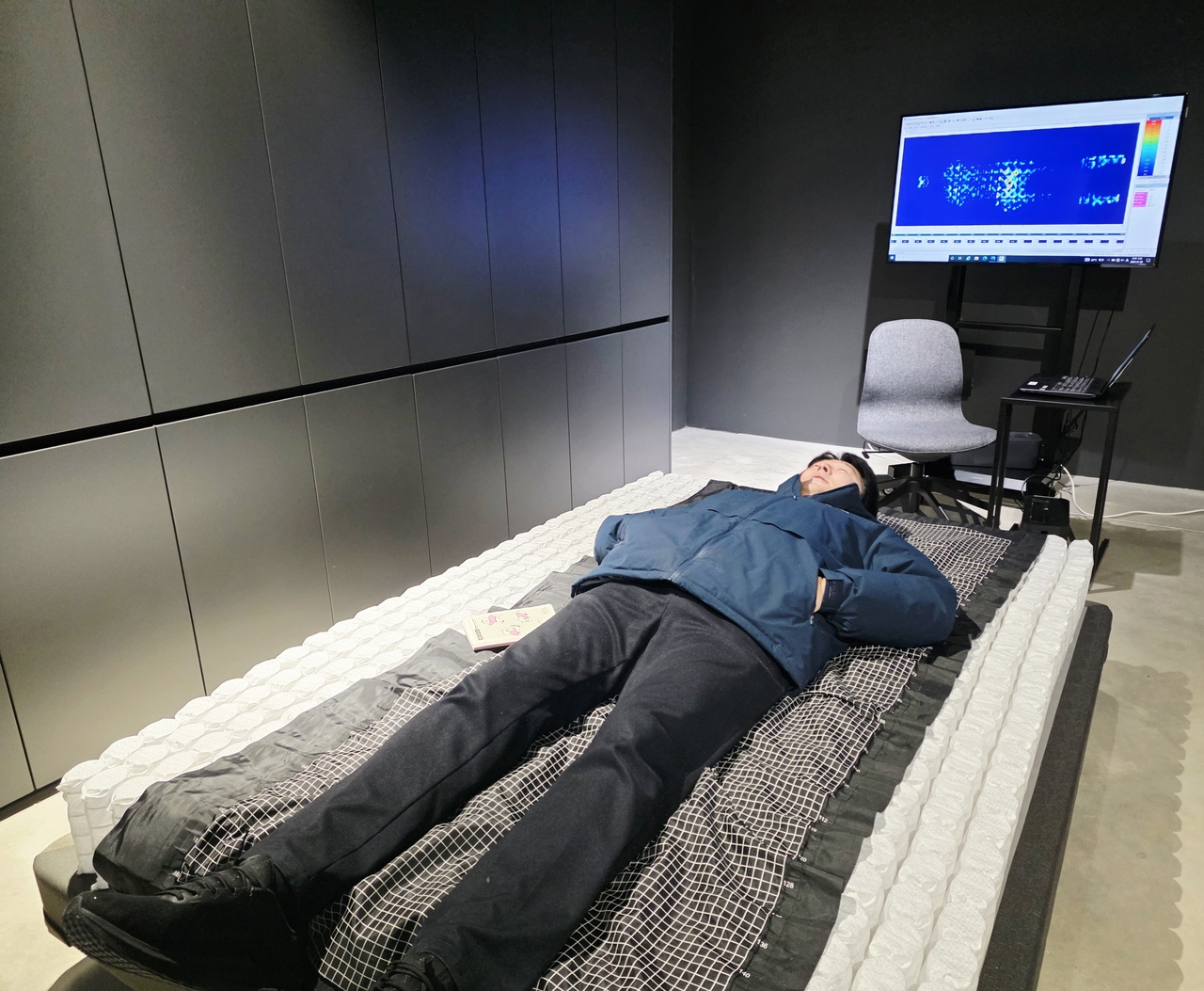 지난 20일 오전 시몬스 R&D 센터 감성과학 분석실에 설치된 침대에 기자가 직접 누워봤다. 포켓 매트리스의 강도가 각각 어느정도가 유지돼야 고객이 느끼는 편안함이 극대화 될 수 있는지를 체크하는 것이 포인트다. 기자가 누운 지점에 맞게 상단 모니터에 눌림 강도가 표시 되고 있다. [시몬스]