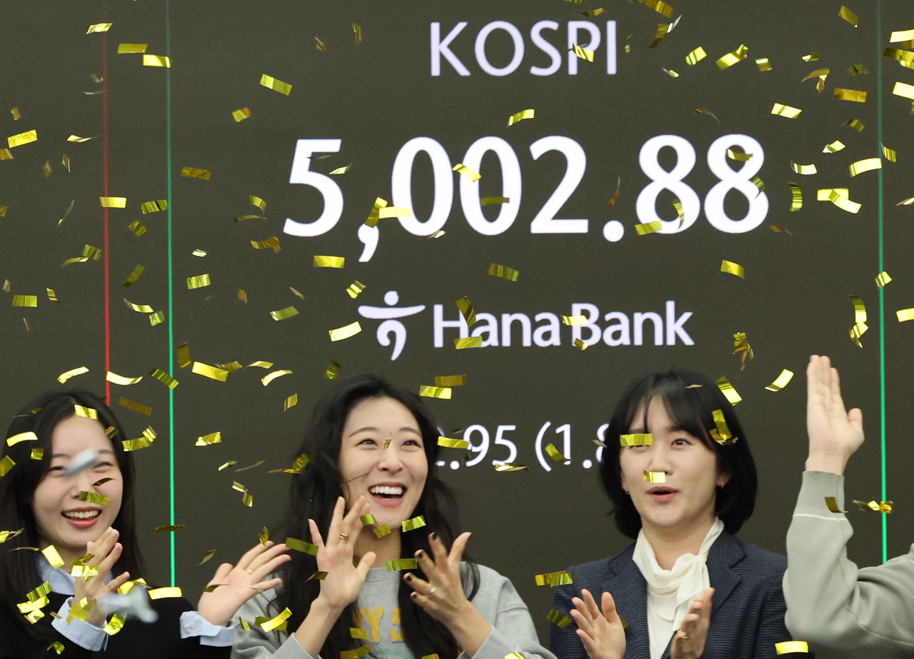As the Kospi surpassed the 5,000 mark during intraday trading, foreign exchange dealers hold a celebratory ceremony at the Hana Bank dealing room in central Seoul on Thursday morning. (Yonhap)