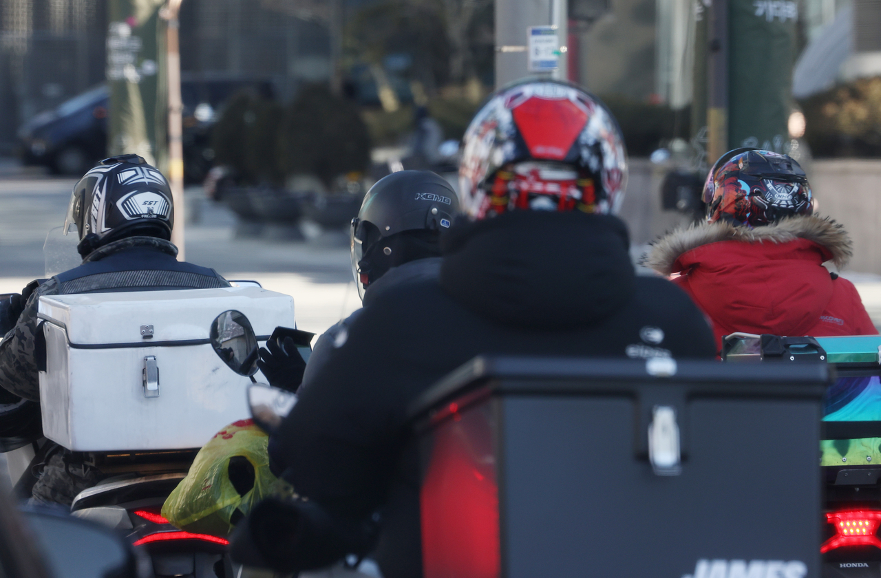 Delivery riders travel along a road in Seoul on Dec. 22. (Yonhap)