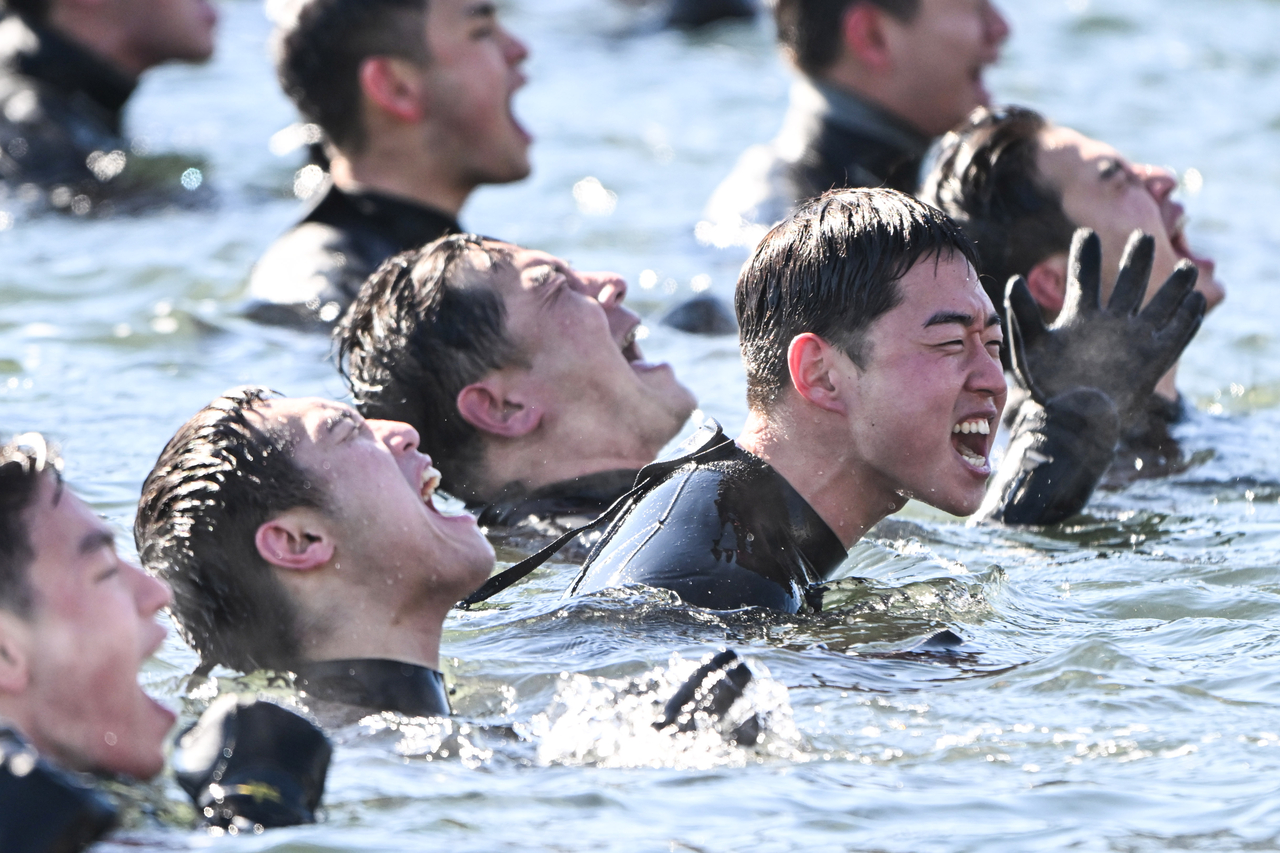 Navy deep-sea divers shout slogans in the water during cold-weather endurance training at Jinhae Naval Port in Jinhae District, Changwon, South Gyeongsang Province, on Thursday.  (Yonhap)