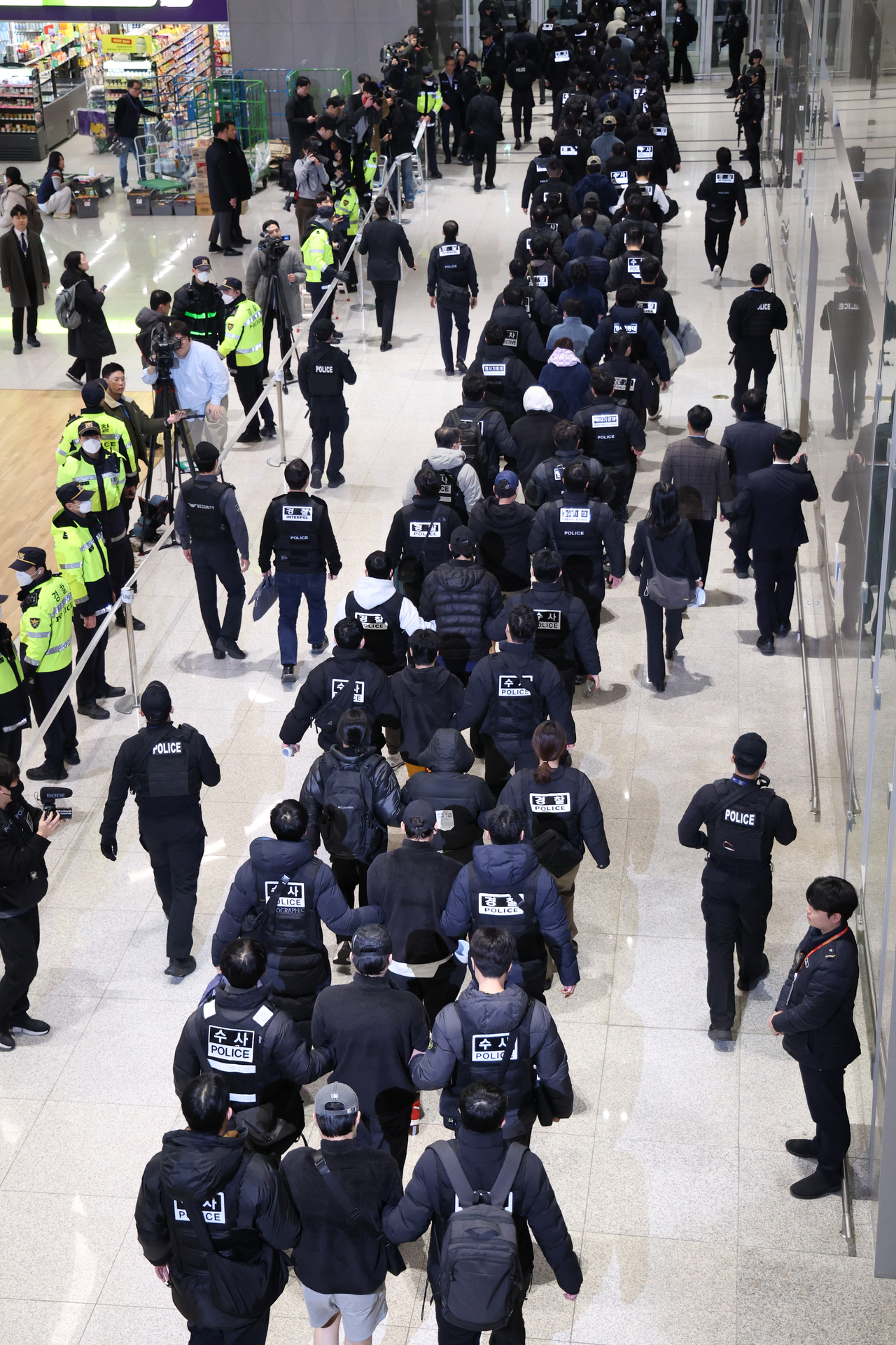 Police escort South Korean criminal suspects at Incheon Airport after their repatriation from Cambodia on Friday. (Yonhap)