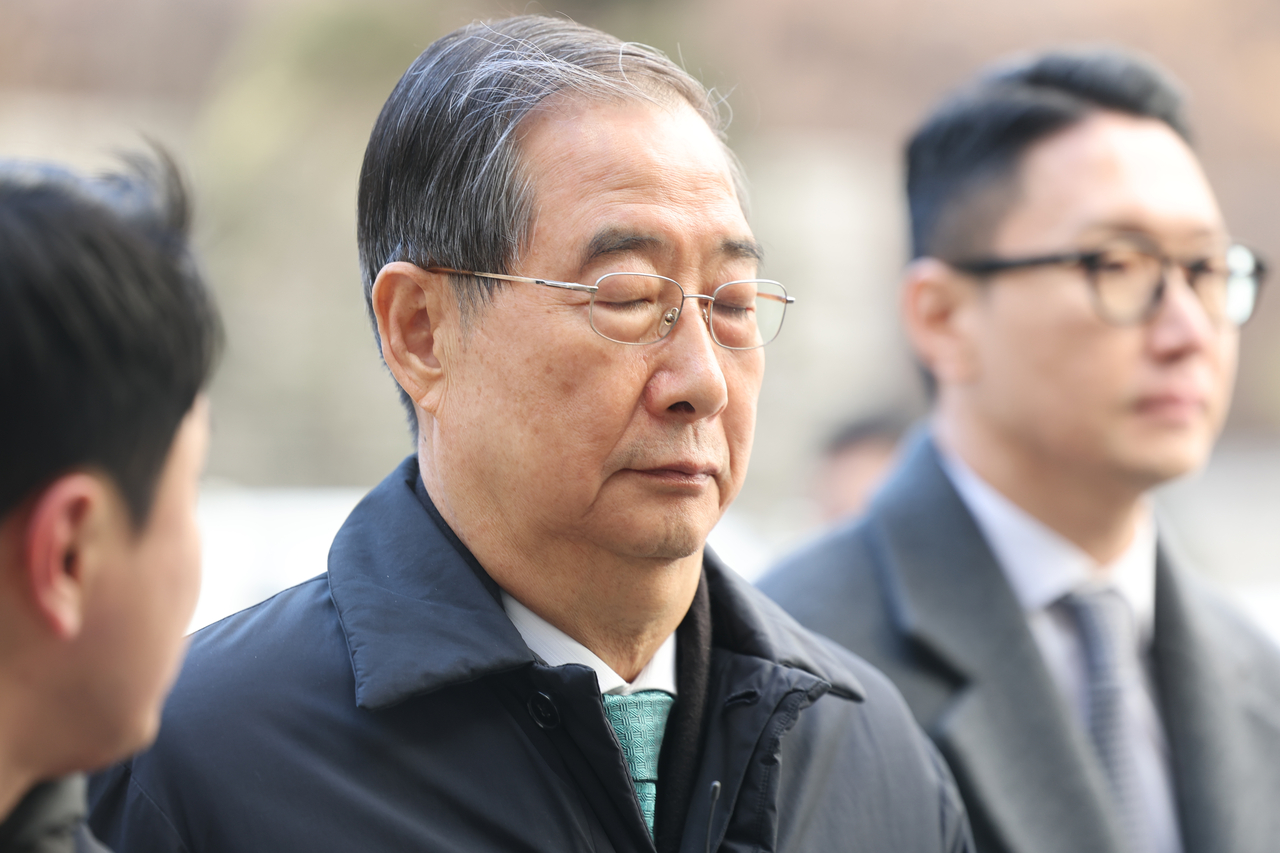 Former Prime Minister Hand Duck-soo (center) arrives at the Seoul Central Distric Court on Wednesday to attend his sentencing. (Yonhap)