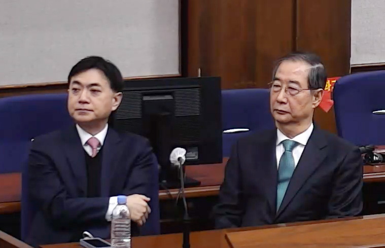 Former Prime Minister Han Duck-soo (right) attends his sentencing on Wednesday for his charge of playing a key role in an insurrection. (Yonhap)