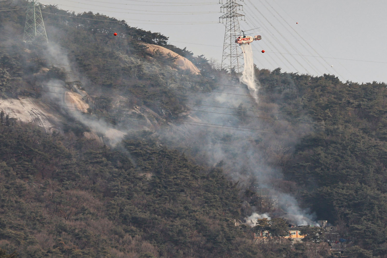 Firefighters extinguish a wildfire at Suraksan in northern Seoul on Monday. (Newsis)