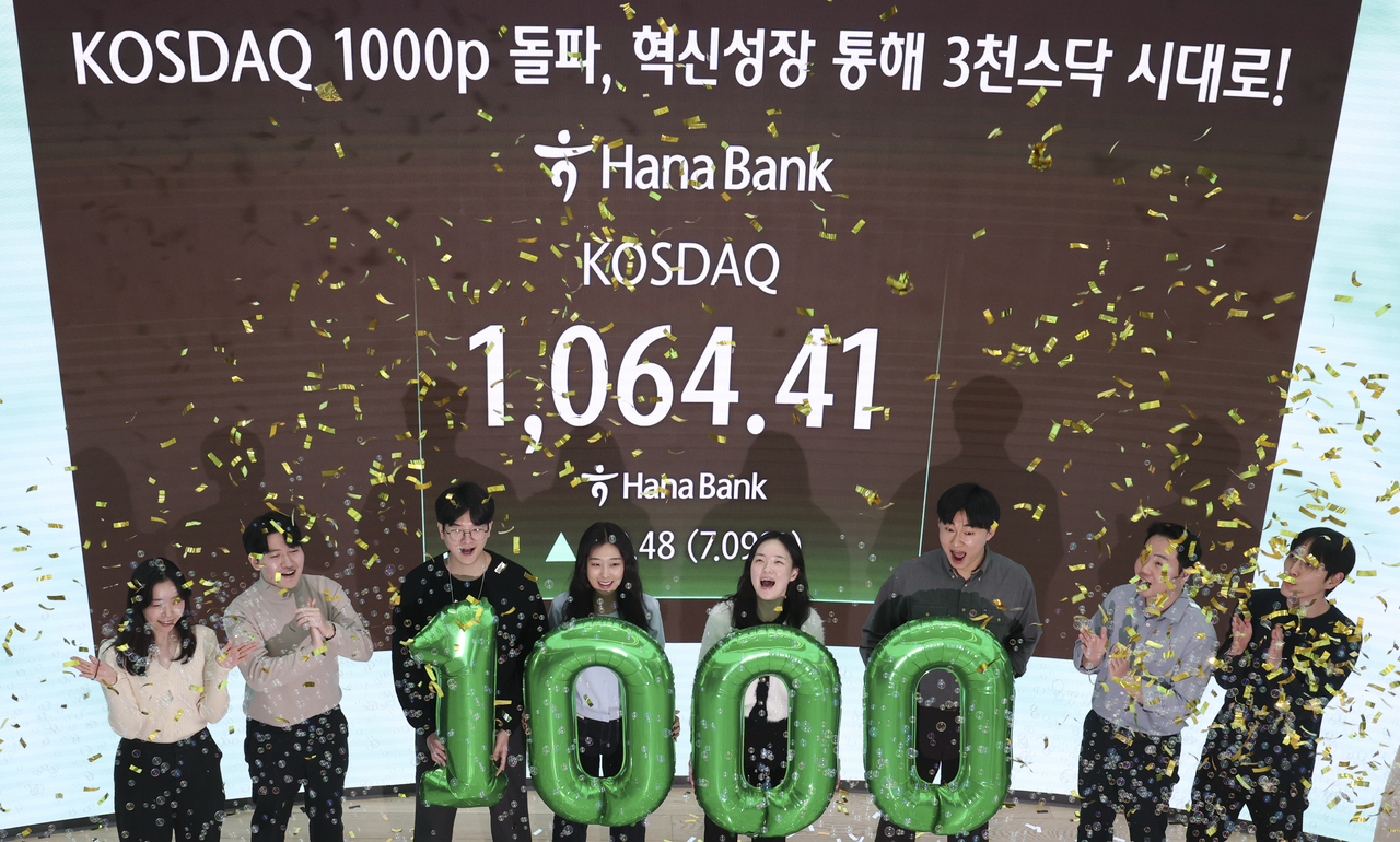 Traders celebrate the secondary bourse Kosdaq surpassing the 1,000-point mark for the first time in four years, closing at 1,064.41 at the dealing room of Hana Bank in central Seoul. (Joint Press Corps.-Yonhap)