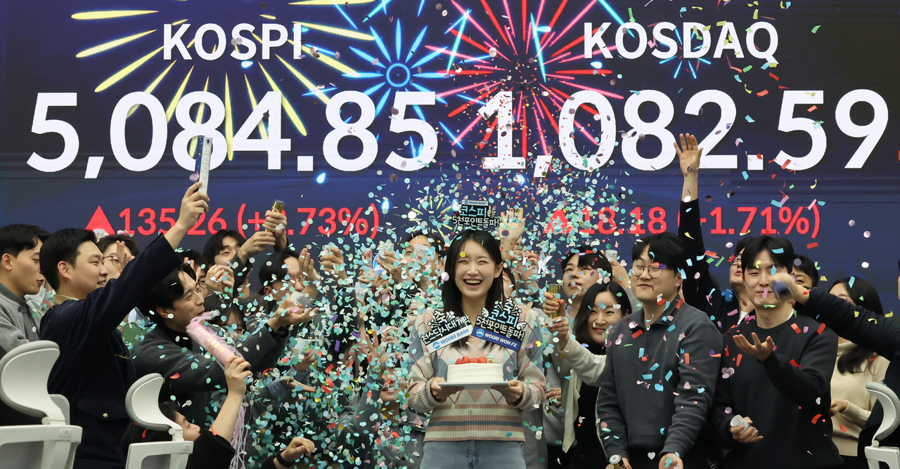 Traders celebrate the benchmark Kospi surpassing the 5,000-point mark for the first time at Woori Bank’s dealing room in central Seoul on Tuesday. The Kospi closed at 5,084.85, while the Kosdaq finished the day at 1,082.59. (Yonhap)