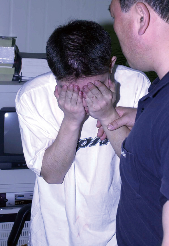 Lee Eun-seok covers his face as he is taken in for police questioning, in this 2000 file photo.