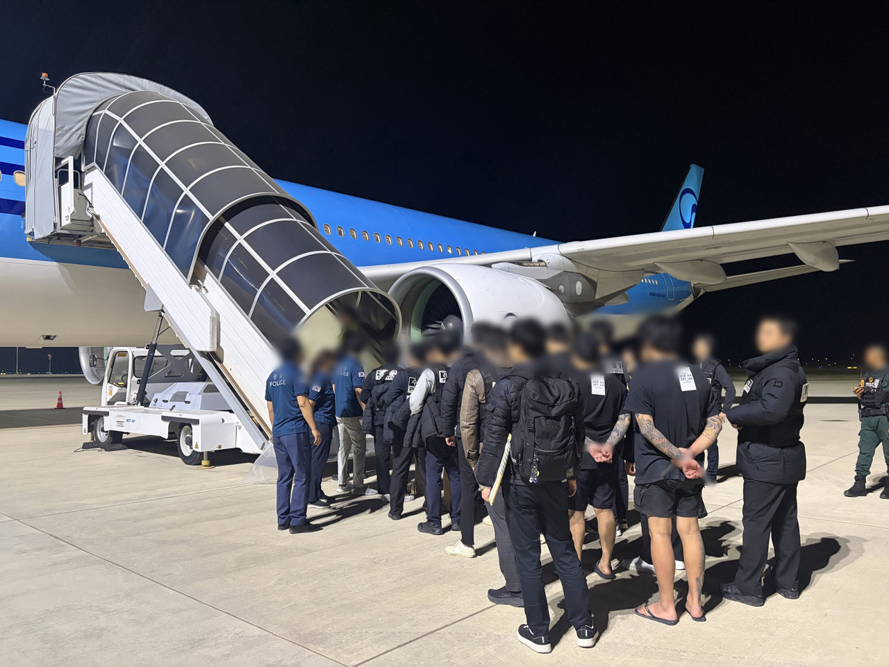 This photo shows South Korean suspects boarding an airplane in Phnom Penh International Airport in Cambodia bound for South Korea on Jan. 23. (Korean National Police Agency)