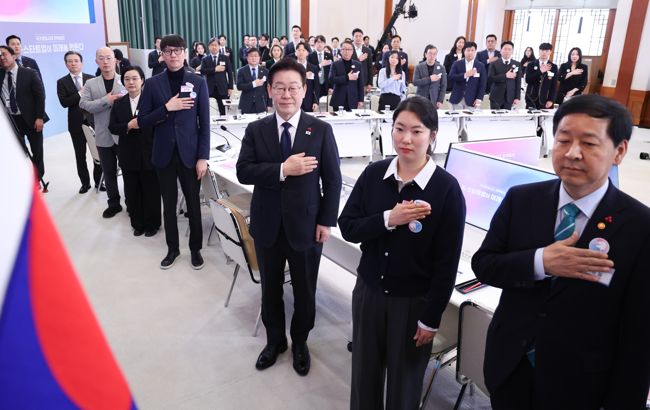 President Lee Jae Myung (third from right) and participants look on at the national flag in a strategic meeting the president convened at Cheong Wa Dae on Friday. (Yonhap)