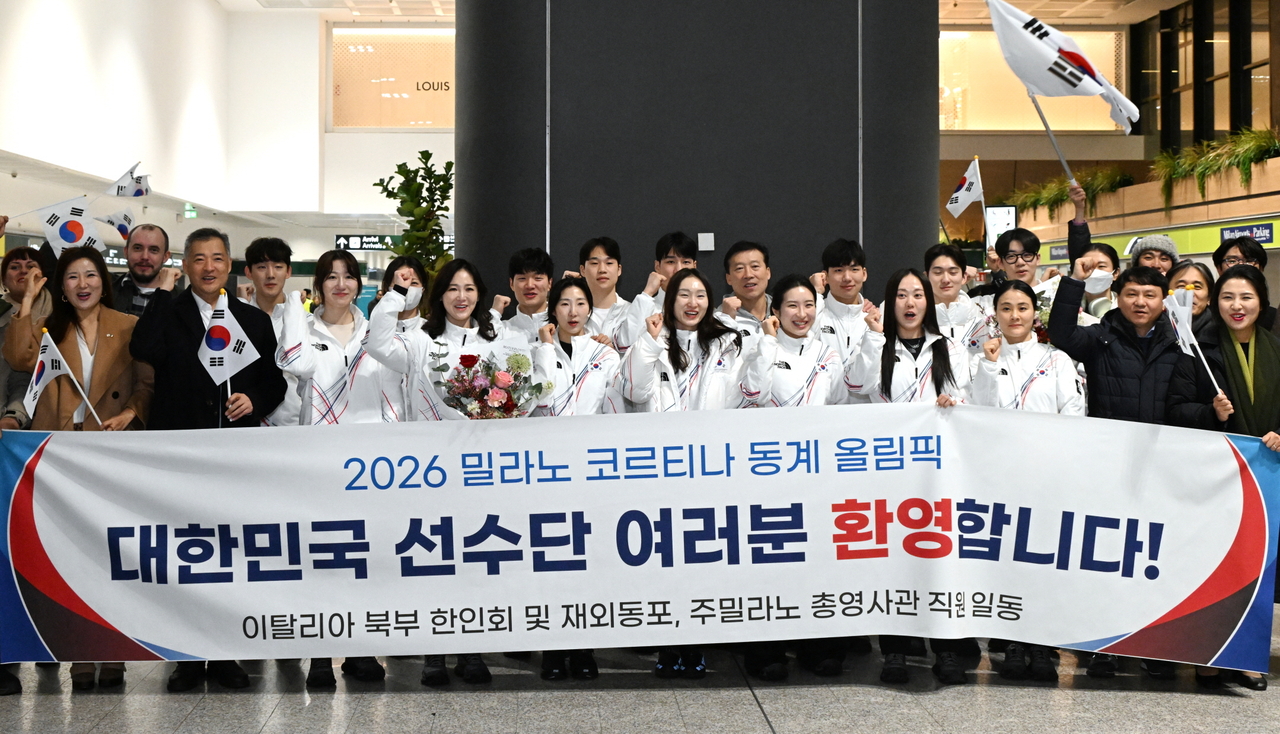 South Korean athletes and officials competing at the 2026 Winter Olympics pose behind a banner from the South Korean community in Milan, welcoming them to the host city of the competition, at Milan Malpensa Airport in Milan, Italy, on Jan. 31, in this photo provided by the Korean Sport & Olympic Committee. (Yonhap)