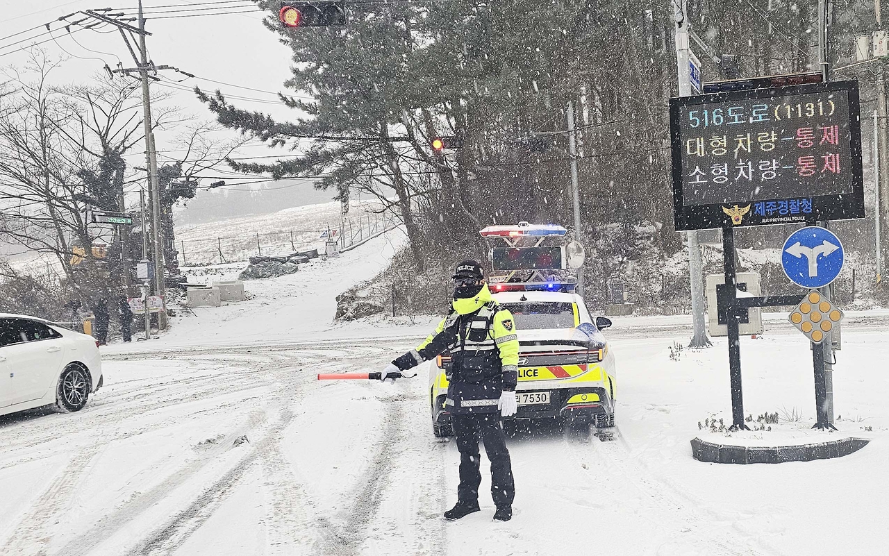 A police officer directs traffic amid heavy snowfall on Jeju Island on Jan. 22. (Yonhap)