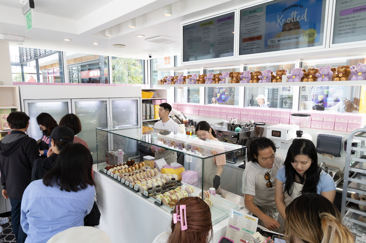 Exterior of Cafe Knotted's first US store in Century City Los Angeles showing the pastel branding and Sugar Bear mascot of the Korean donut chain