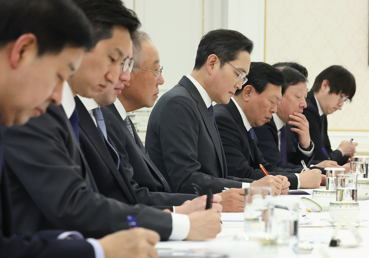 Leaders of South Korea’s major conglomerates take notes as President Lee Jae Myung speaks during the meeting at Cheong Wa Dae on Wednesday. From left: Deputy Prime Minister and Minister of Economy and Finance Koo Yun-cheol, HD Hyundai Chairman Chung Ki-sun, LG Group Chair Koo Kwang-mo, Federation of Korean Industries Chair Ryu Jin, Samsung Electronics Chair Lee Jae-yong, Lotte Group Chair Shin Dong-bin, GS Group Chair Huh Tae-soo and senior presidential secretary for AI and future planning Ha Jung-woo. (Yonhap)