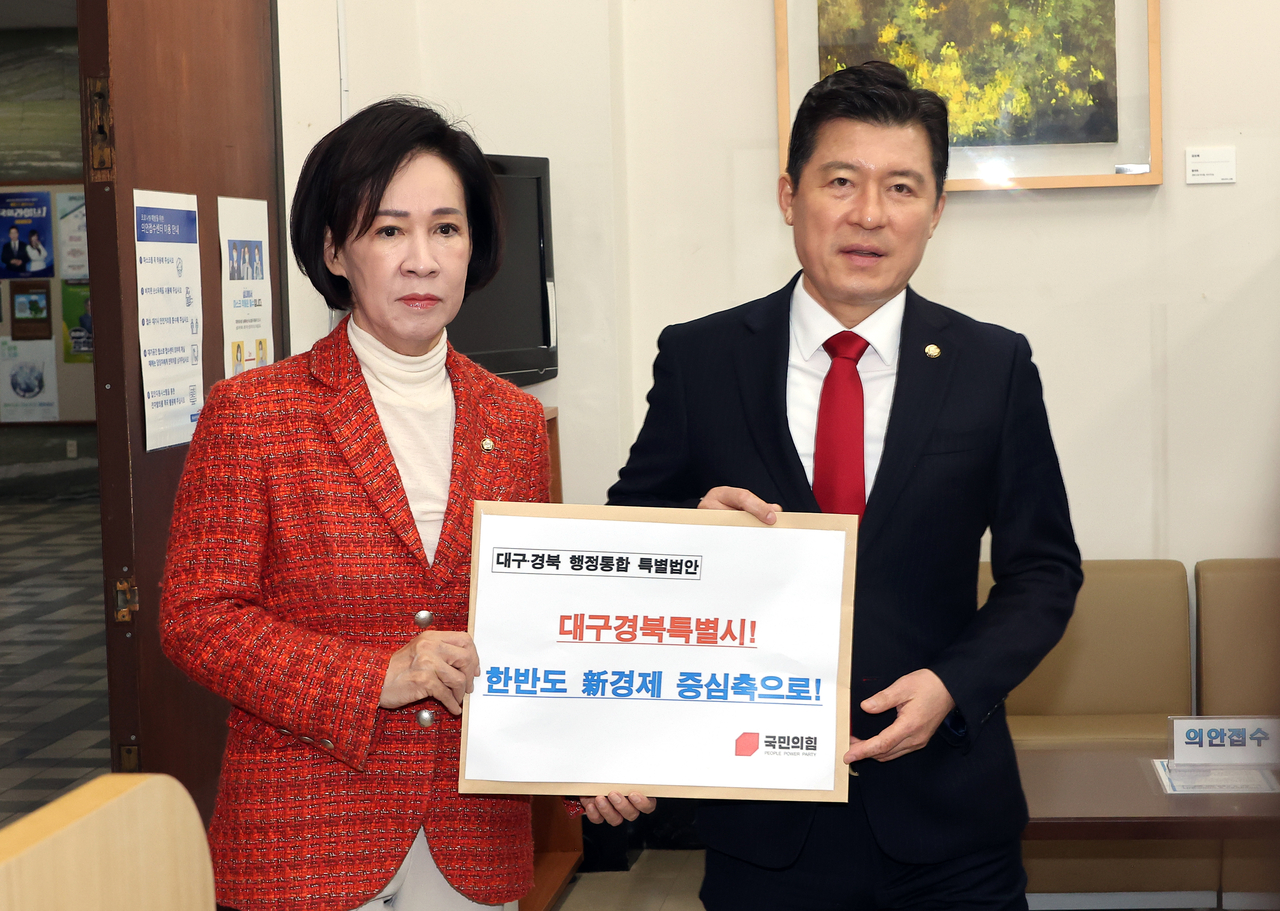 Rep. Lee In-seon (left) and Koo Ja-keun submit the special act bill on administrative integration of Daegu and North Gyeongsang Province to the National Assembly in central Seoul, last Friday. (Yonhap)
