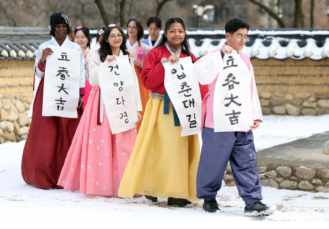 Foreign nationals wearing hanbok, traditional Korean attire, hold up handwritten messages welcoming spring on Monday in Gyeongsan, North Gyeongsang Province. (Yonhap)