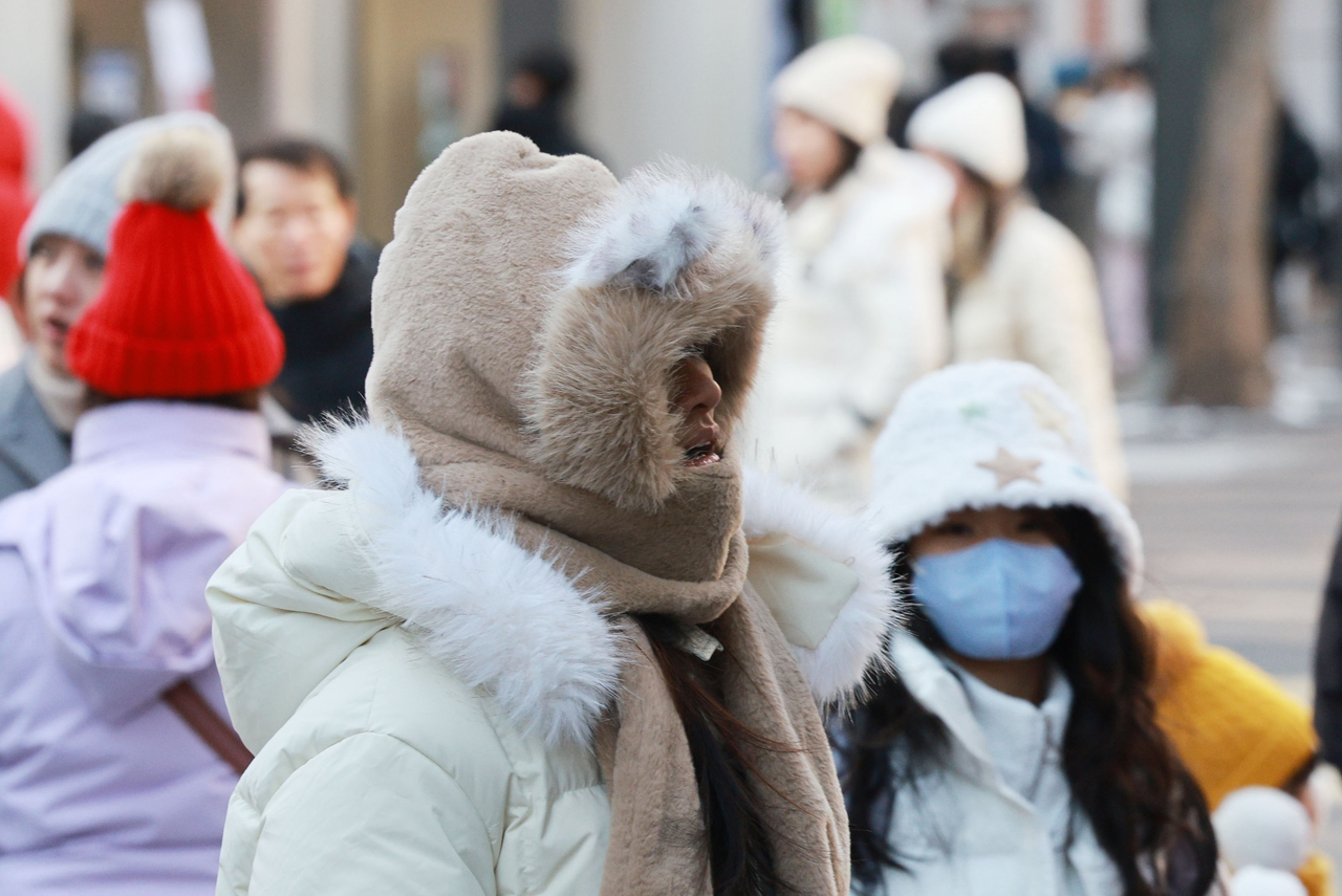 Foreign tourists heavily armed with thick winter coats walk in a street in Myeongdong, central Seoul, in this file photo taken Jan. 25. (Yonhap)