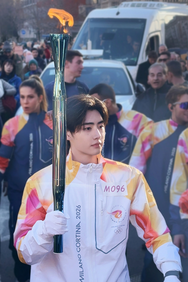 Enhypen's Sunghoon walks with the Olympic torch near Milan’s Bolivar Station on Friday. (Belift Lab)
