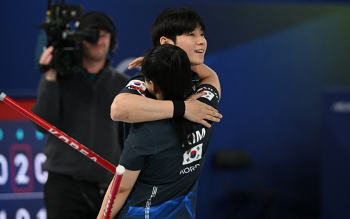 Jeong Yeong-seok (L) and Kim Seon-yeong of South Korea celebrate their victory over the United States in the round-robin match of the mixed doubles curling tournament of the Winter Olympics at Cortina Curling Olympic Stadium in Cortina d'Ampezzo, Italy, on Saturday. (Reuters-Yonhap)