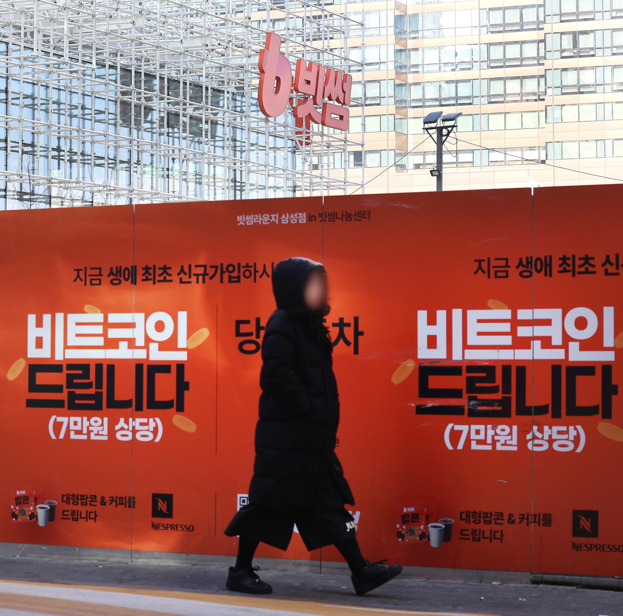 A person walks past an advertisement for a promotional event by Bithumb, a South Korean crypto exchange, in this photo taken Sunday. (Yonhap)