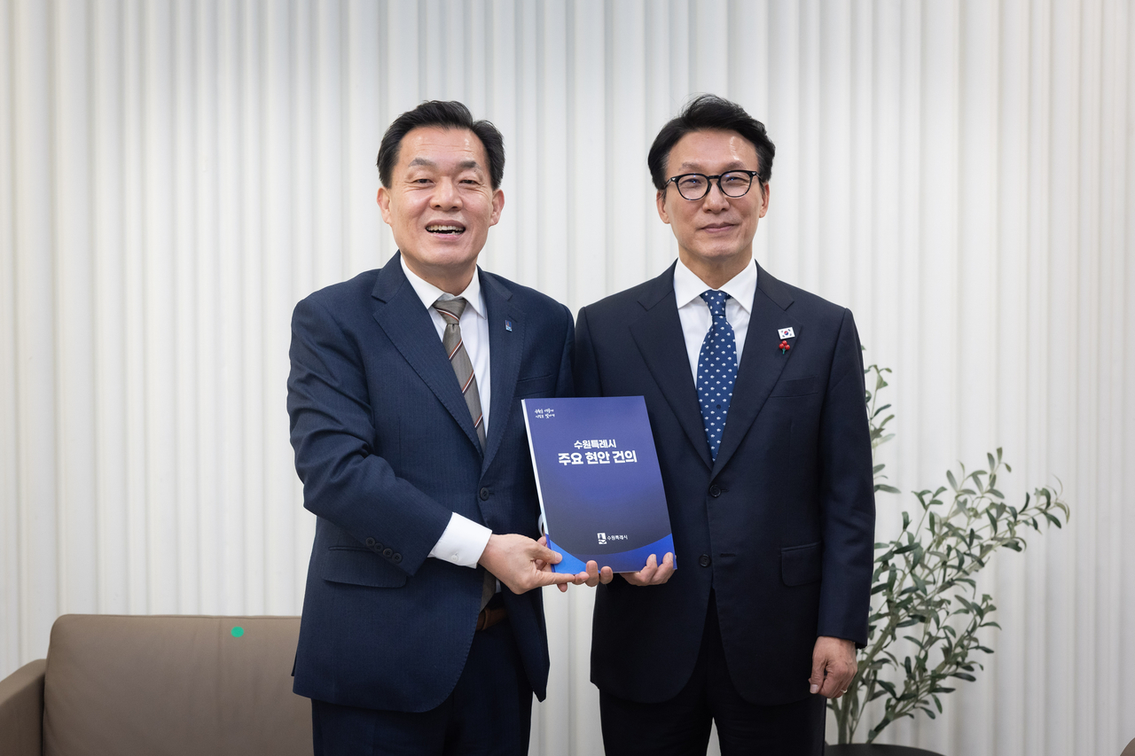 Suwon Mayor Lee Jae-joon (left) poses with Prime Minister Kim Min-seok, holding a booklet titled "Key Agenda of Suwon Special City" during a national policy briefing event at the Suwon Convention Center on Jan. 16. (Suwon Special City)