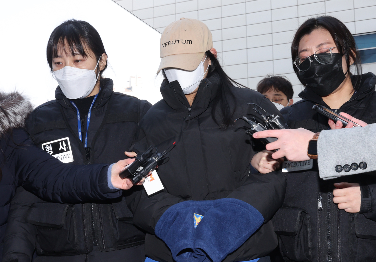 The suspect accused of inducing two deaths (center) is escorted to the hearing for her arrest warrant at the Seoul Northern District Court on Thursday. (Yonhap)