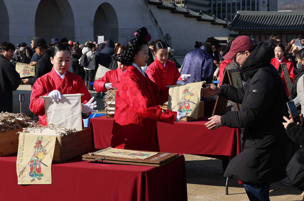 Visitors receive traditional New Year paintings at the “2026 Byeong-o Year Sehwa Sharing” event held at Heungnyemun Square of Gyeongbokgung Palace in Seou on Monday, a day before the Lunar New Year holiday. (Yonhap)