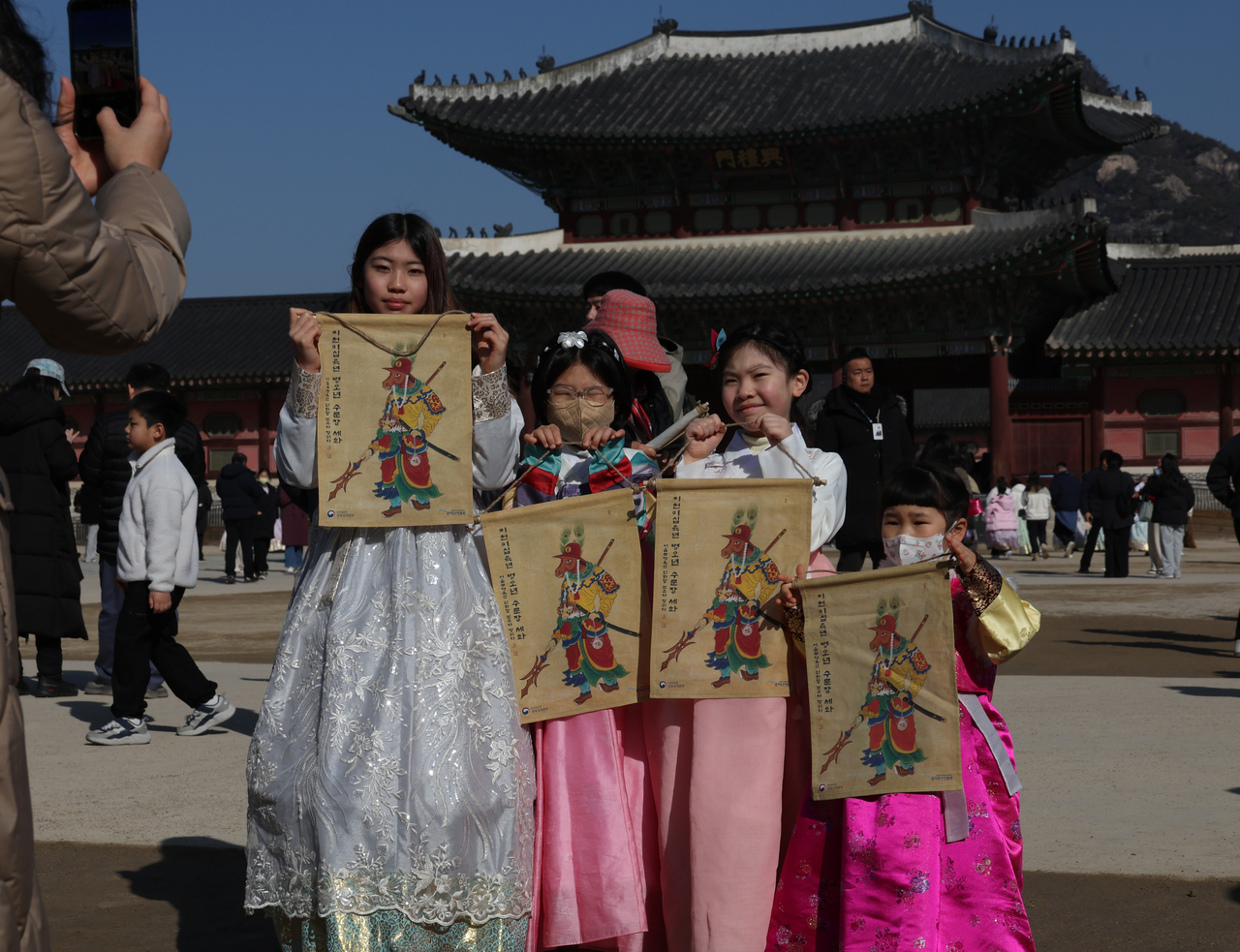 Visitors pose for a commemorative photo while holding traditional New Year paintings at the “2026 Byeong-o Year Sehwa Sharing” event held at Heungnyemun Square of Gyeongbokgung Palace in Seoul on Monday, a day before the Lunar New Year holiday. (Yonhap)