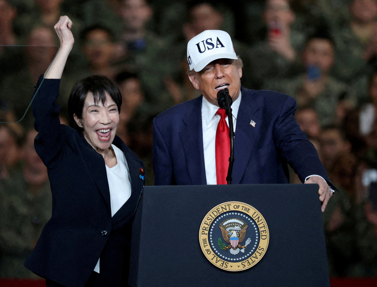 US President Donald Trump (right) speaks as Japanese Prime Minister Sanae Takaichi gestures towards military personnel, aboard the aircraft carrier USS George Washington, during their visit to the US Navy's Yokosuka base in Yokosuka, Japan, Oct. 28.   Reuters-Yonhap