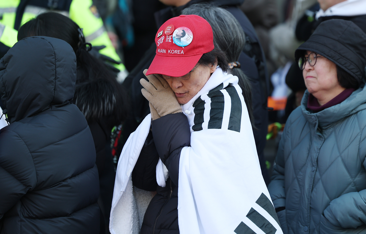 A supporter of Yoon Suk Yeol on Thursday expresses disappointment after learning of the verdict in front of the Seoul Central District Court in Seocho-gu, Seoul. (Yonhap)