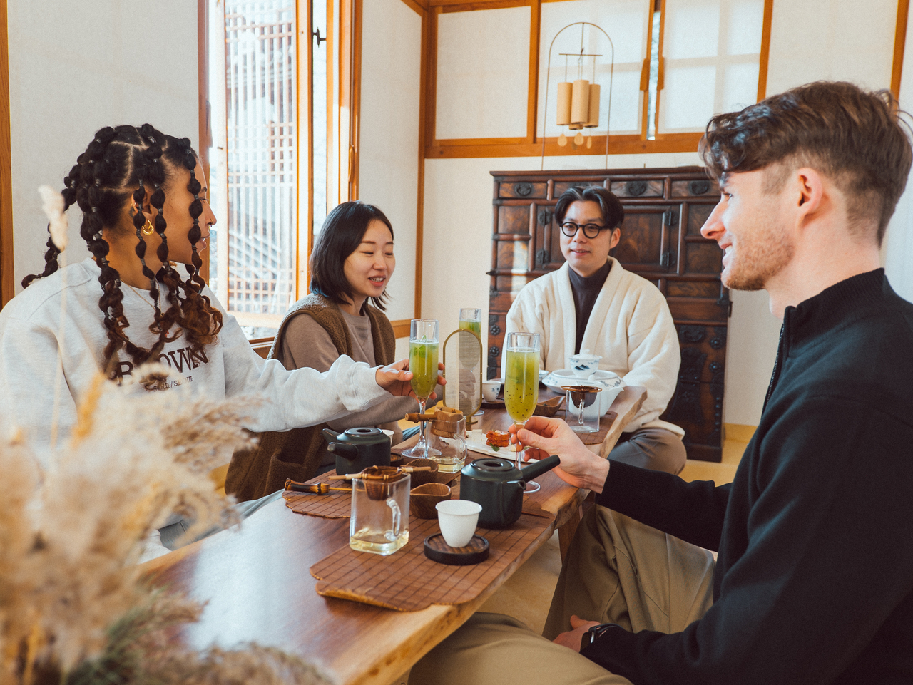 Visitors gathered inside a traditional hanok with wooden beams and paper-screen doors during a Bukchon hanok stay program in Seoul