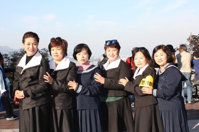 Tourists pose for a photo wearing old school uniforms from the 1970s and 1980s. (Herald DB)