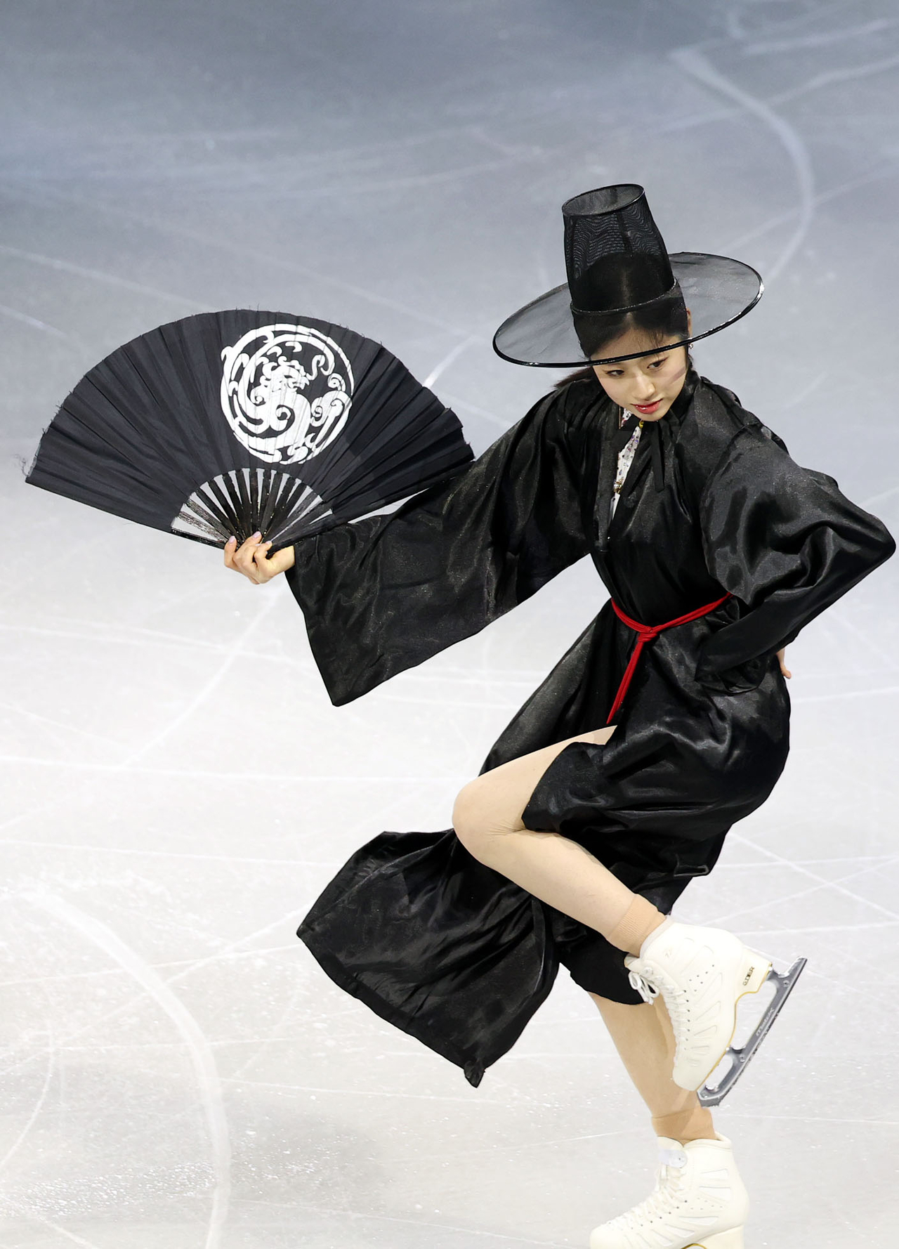Lee Hae-in skates while dressed as a grim reaper-type figure in Korean tradition, with a black gat atop her head while holding a black fan and wearing a black durumagi coat. (Yonhap)