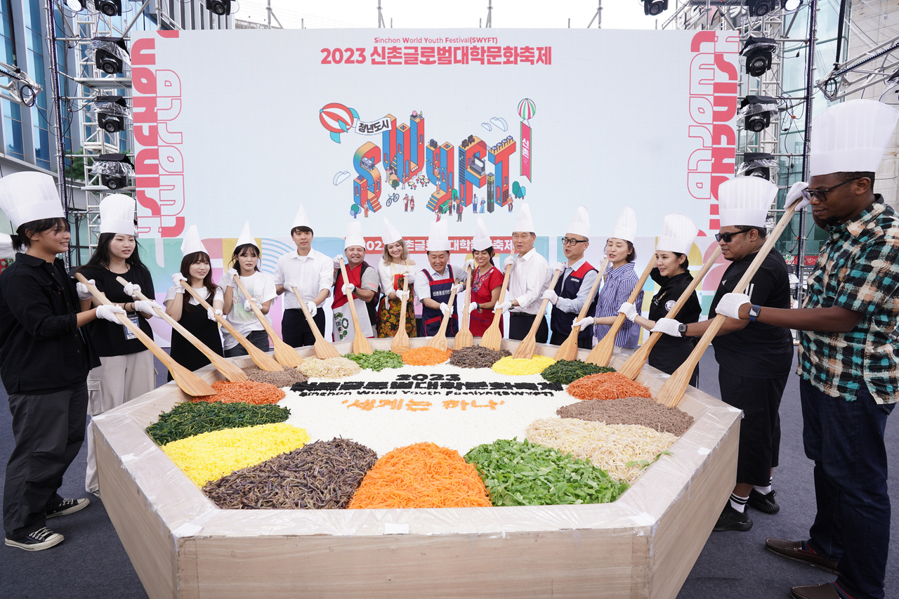 Seodaemun-gu Mayor Lee Seong-heon (sixth from right) and international participants in the 2023 Sinchon World Youth Festival pose before making a giant bibimbap in Seodaemun-gu, Seoul. (Seodaemun-gu Office)