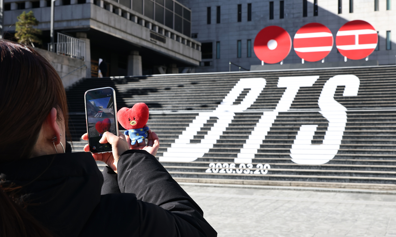 Tourists take photos in front of a promotional display announcing the return of BTS on the steps of the Sejong Center for the Performing Arts in Jongno District, Seoul, Feb. 22. (Yonhap)