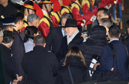 Brazilian President Luiz Inacio Lula da Silva (C with hat) is welcomed by the South Korean delegation upon his arrival at Seoul Air Base in Seongnam, south of Seoul, on Sunday. (Yonhap)