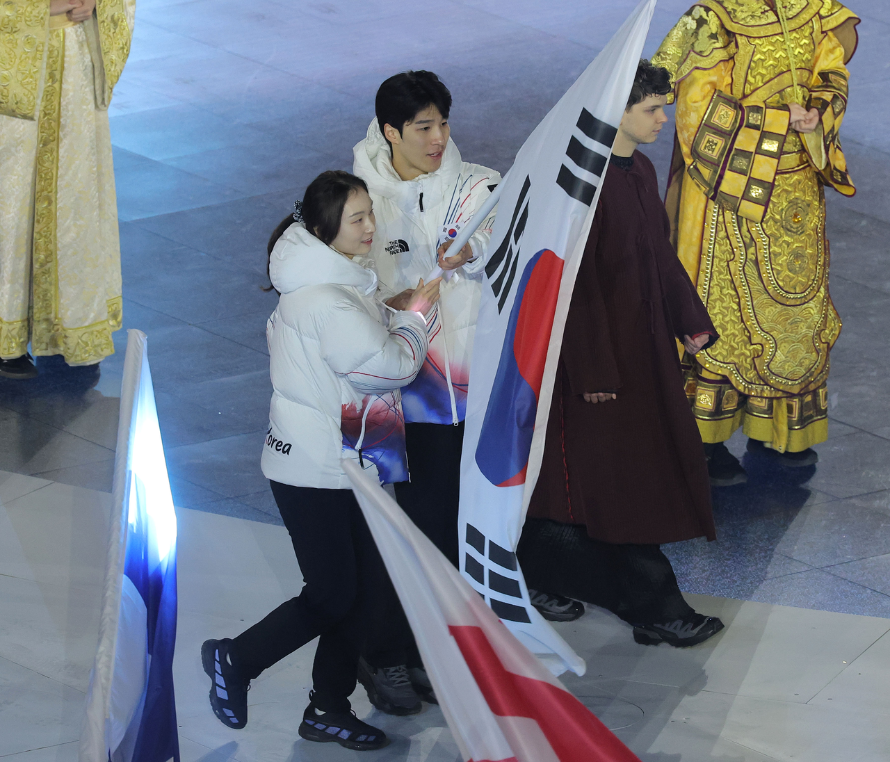 Choi Min-jeong and Hwang Dae-heon, serving as flag bearers, enter carrying the South Korean flag during the closing ceremony of the Milano–Cortina d’Ampezzo 2026 Winter Olympics at the Arena di Verona on Sunday. (Yonhap)