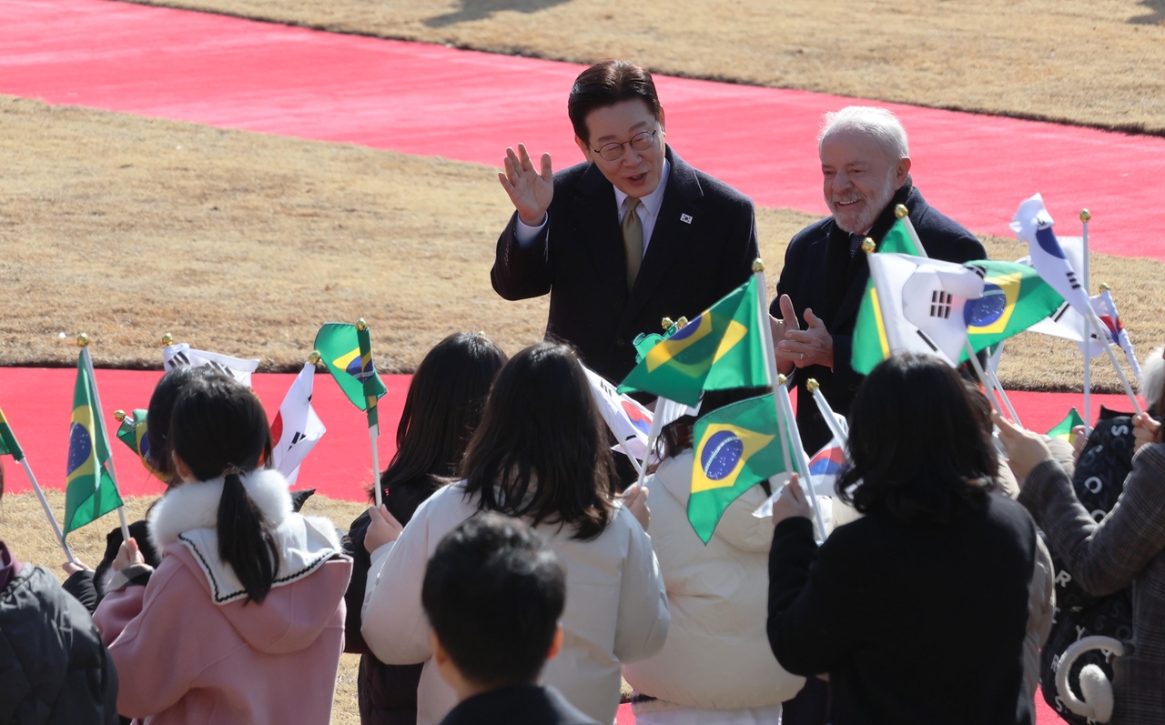 South Korean President Lee Jae Myung (left) and Brazilian President Luiz Inacio Lula da Silva meet with children as they attend a welcome ceremony for the Brazilian leader prior to their summit talks at the presidential office Cheong Wa Dae in Seoul on Monday. (Yonhap)