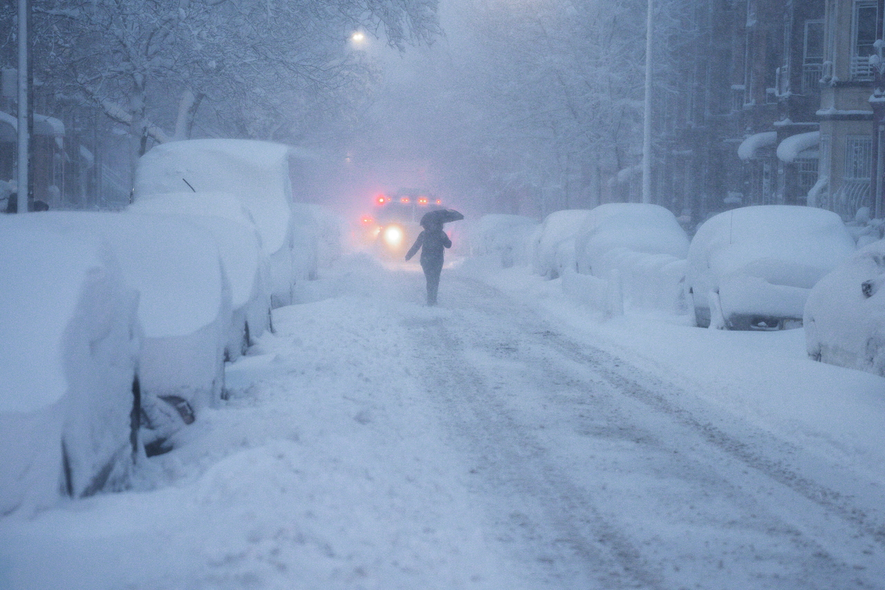 A erson walks down the road in front of a snowplowing vehicle in there Brooklyn borough in New York, Monday. (EPA-Yonhap)