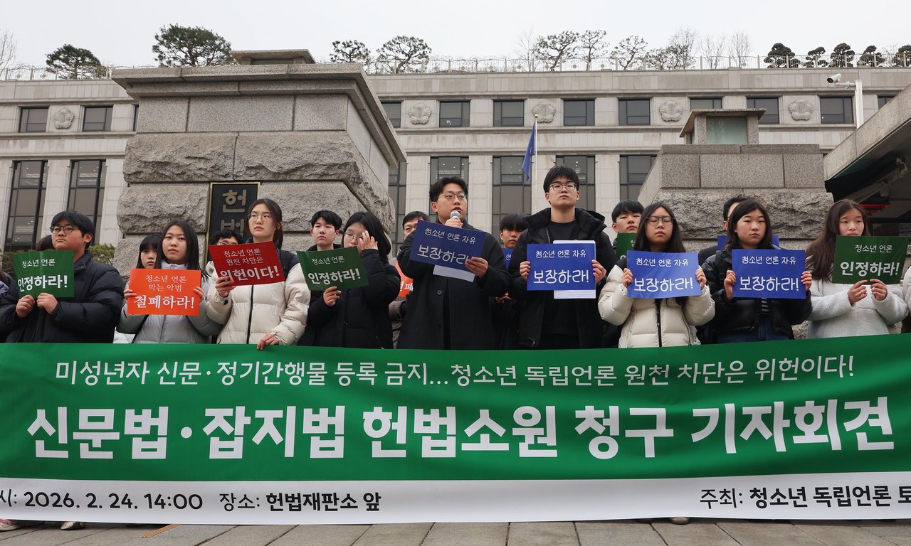Student journalists from Tokipul, including Moon Sung-ho (front, fourth from right), hold up signs during a press conference on Tuesday in front of the Constitutional Court, before submitting their constitutional complaint. (Yonhap)